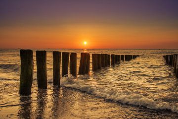 Zonsondergang in Domburg tussen de golfbrekers. van Rick van de Kraats