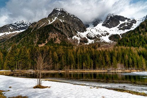 A frozen lake in the Alps with heavy clouds hanging over the mountains