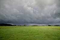 Onheilspellende donkere onweerslucht boven groen polderlandschap