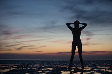 Artistique silhouette nue avec le coucher du soleil dans la mer des Wadden sur Arjan Groot