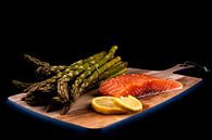 Fresh green asparagus, raw salmon and lemon slices on a wooden plank by Dafne Vos thumbnail