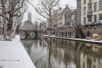 Schnee entlang des Oudegracht-Kanals mit dem Dom-Turm im Hintergrund an einem Wintertag in Utrecht, 