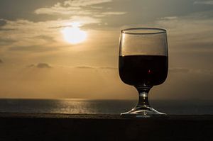 Nahaufnahme eines Weinglases gegen einen romantischen Sonnenuntergang