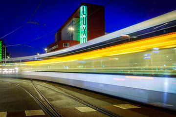 Das alte Luxor-Theater in Rotterdam Holland mit einer Straßenbahn im Vordergrund am Abend.
