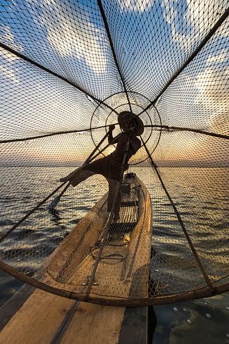 Visser die met traditionele boot op het Inle meer in Myanmar op ouderwetse wijze met een vis korf vi van Wout Kok