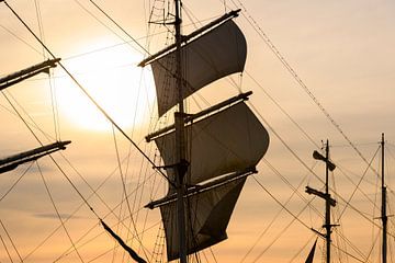 Masten van oude zeilschepen met de zon in de achtergrond