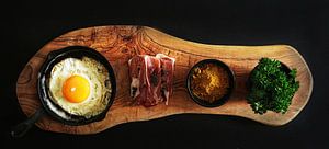 Stilleben mit Spiegelei, Schinken und Kräutern.