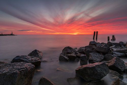 Het IJsselmeer bij Den oever onder een ochtendrode wolkenlucht