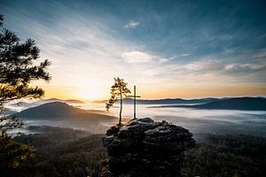 Baum mit Kreuz auf Felsklippe Sonnenaufgang in Landschaft