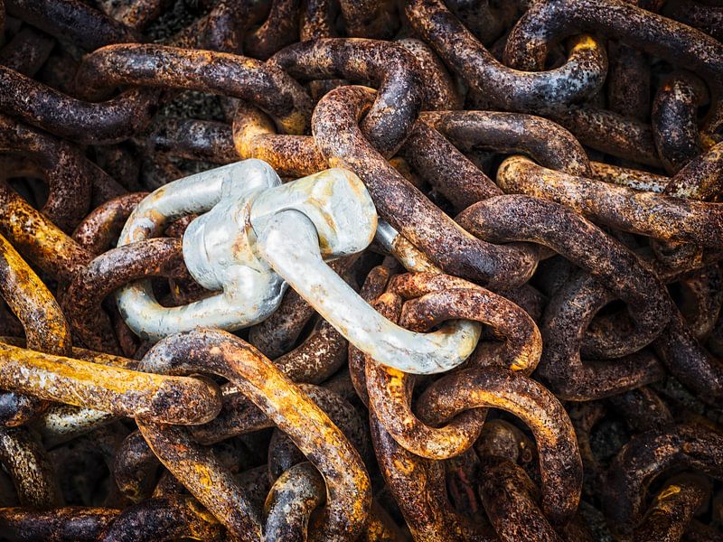 Eine Nahaufnahme von verrosteten Metallkettengliedern mit einem glänzenden Silberhaken von Luc V. de Zeeuw