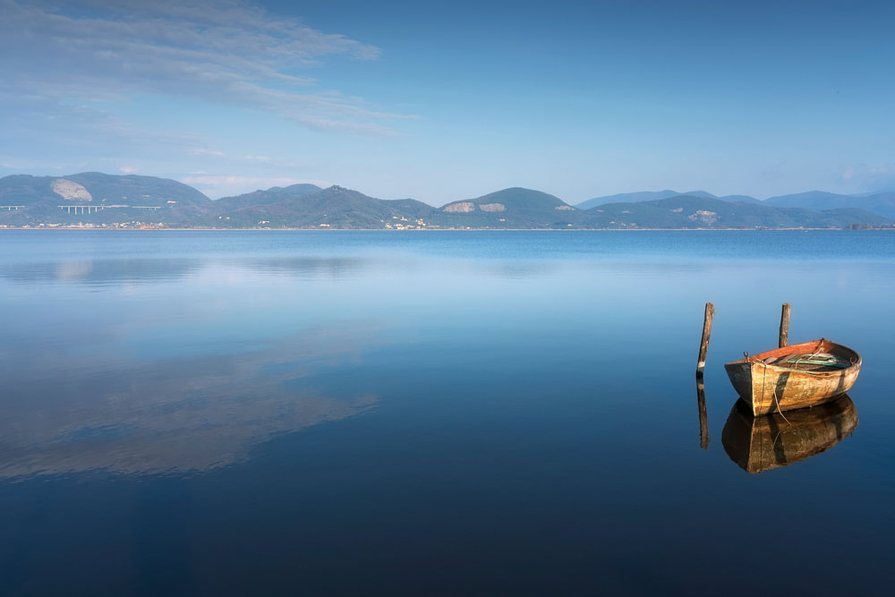 Houten boot aangemeerd in het Massaciuccoli-meer in Toscane van Stefano ...