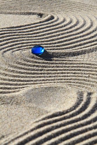 Sporen in het zand met blauwe steen