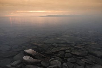 Coucher de soleil doré et eau claire du lac Baïkal profond, les pierres au fond sont visibles. sur Michael Semenov