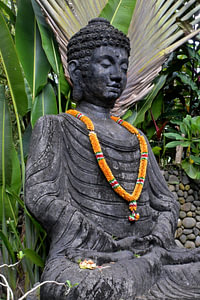 Buddha-Statue mit Blumengirlande in einem balinesischen Garten