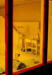 Schaufenster mit rotem Rahmen – Stuhl, Beistelltisch & Warmlicht