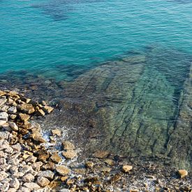 Blauw zeewater in een rotsachtige baai van Adriana Mueller
