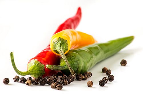 Macro red yellow green peppers and pepper on white