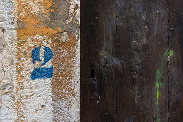 Rustikale braune Holztür mit blauer Hausnummer 2 von Wil Wijnen