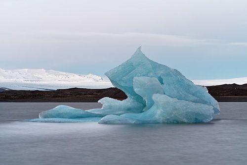 Big blue iceberg in front of a glacier