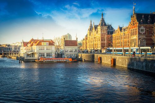 Het centraal station en rondvaartboten in de zon met wolken er boven in Amsterdam