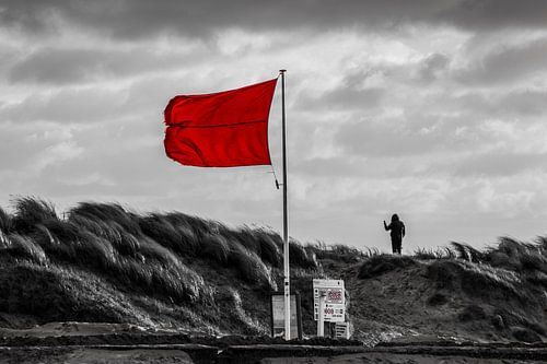 Rode stormvlag op de zuidpier en dreigende wolken