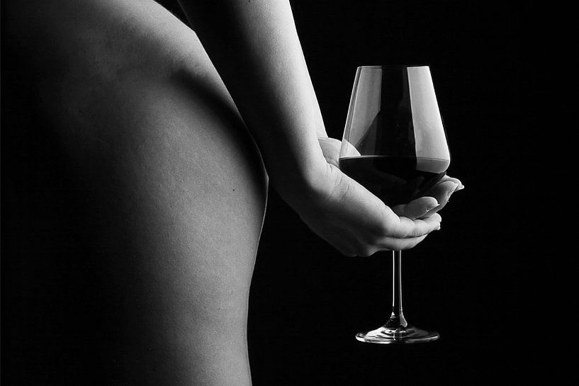 Een foto van een naakte vrouw die een glas wijn vasthoudt achter haar rug.  van Retinas Fotografie