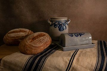 das Stillleben auf einer schönen Leinwand mit einer Butterdose und zwei Brotlaiben