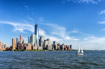 View of Manhattan in New York over the water with sailboat in the foreground.