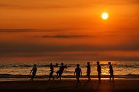 Strandvoetbal bij zonsondergang