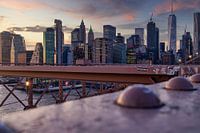 De skyline van New York van de Brug van Brooklyn bij zonsondergang in de Winter met wolken in de hem