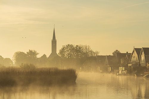 De kerk van Schermerhorn gehuld in mist tijdens een gouden zonsopkomst