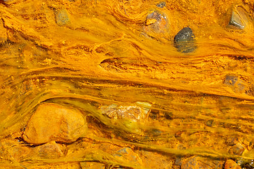 Abstract golden-yellow mineral pattern in a volcanic flow