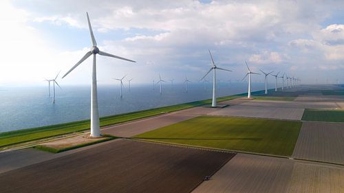 Windturbines langs de kust met tractor op akker
