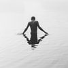 A boy stands in a lake shrouded in fog. by Robin van Steen