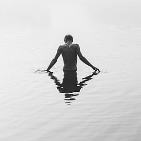 A boy stands in a lake shrouded in fog. by Robin van Steen