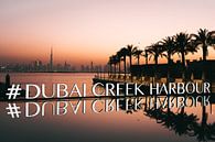 # Dubai Creek Harbour met palmbomen, de skyline en oranje lucht na zonsondergang van Michiel Dros thumbnail