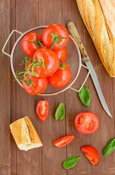 Frische Tomaten liegen in einem Küchensieb auf einem Holztablett