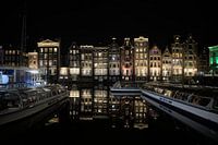 Nachtelijke Reflecties: Grachtenpanden en Rondvaartboten op het Damrak