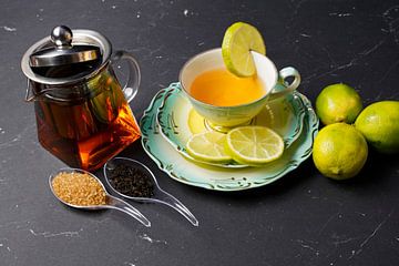 Schwarzer Tee mit Limette, arrangiert auf einem Platzset mit Früchten