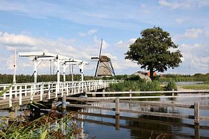 Kinderdijk mit Blick auf eine Brücke mit einer Windmühle und gestapelten Wolken im Hintergrund
