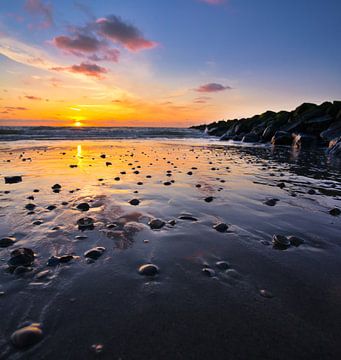 De zon weerspiegeld op het natte zand