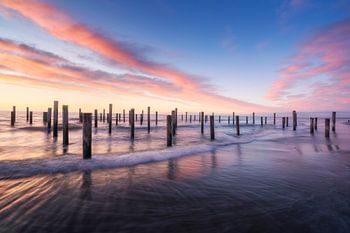 Coucher de soleil serein sur des poteaux en bois à la plage de Petten, Pays-Bas