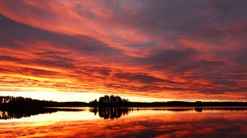 Zonsopgang met een vurige wolkenlucht weerspiegeld in het Ösjön meer. van Aagje de Jong