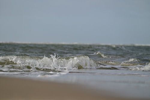 Small wave crashes onto the beach