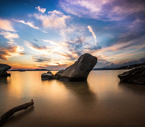 Coucher de soleil sur la côte grecque avec plage, pierres et bâton