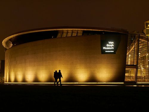 Twee mensen lopen voor het Van Gogh Museum bij nacht