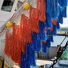 orange and blue fishing nets hang to dry in the harbor by W J Kok