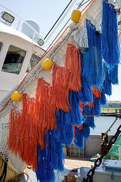 orangefarbene und blaue Fischernetze hängen zum Trocknen im Hafen von W J Kok