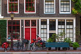 Grachtenpand in Amsterdam met rode deuren en motorrijder in rood by Suzan Baars