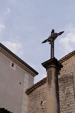 Fotoabzug eines Kreuzes auf einer Statue in der belebten französischen Stadt Ruoms in der sonnigen R von Fotograaf Elise